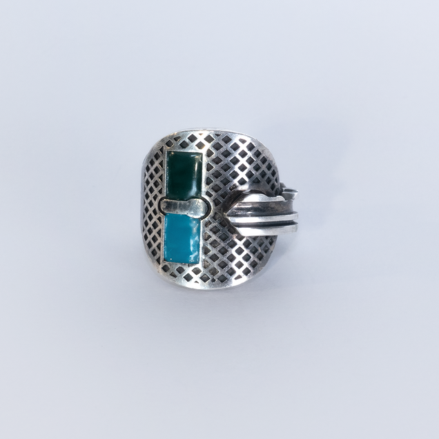 Silver key bent into a ring, two rectangular areas are filled with dark green and turquoise enamel