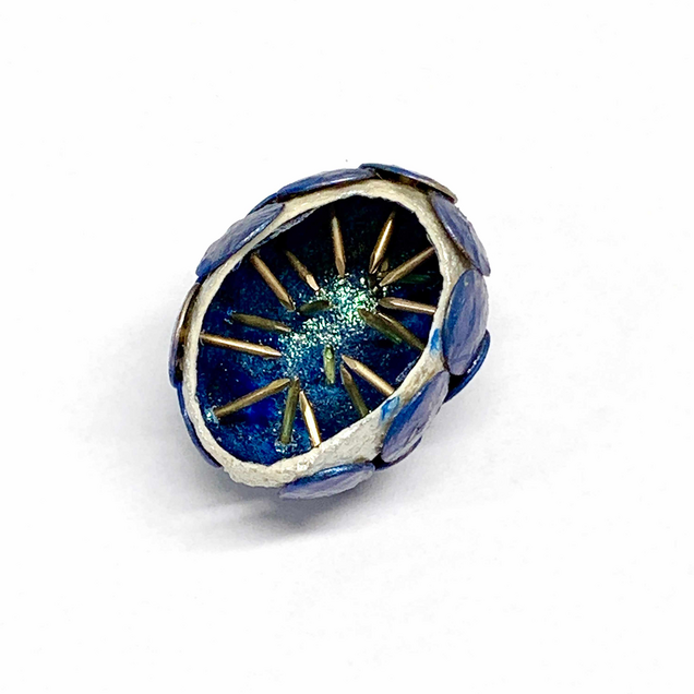 Pendant made of a half silver silk cocoon, pierced with many blue thumbtacks, the inside is painted with glittering blue
