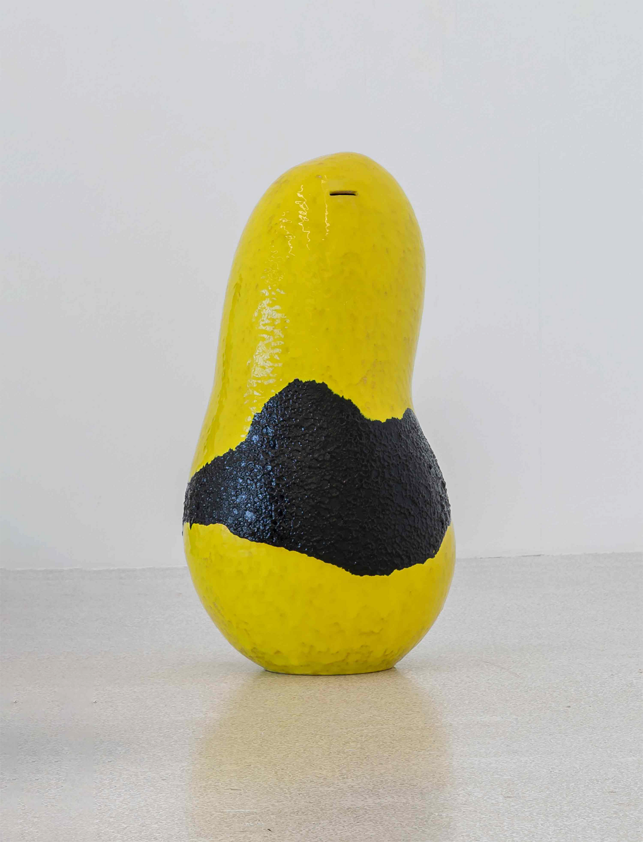 Gelb-schwarze Spardose aus Keramik mit grober Oberflächenstruktur, die auf dem Boden steht