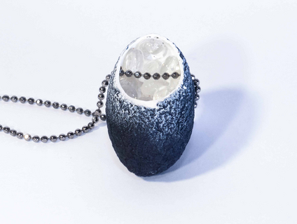 Necklace with a black silk cocoon pendant whose white inside is filled with small glass balls, the chain is made of silver