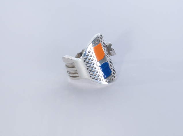 Silver key bent into a ring, two rectangular areas are filled with orange and dark blue enamel