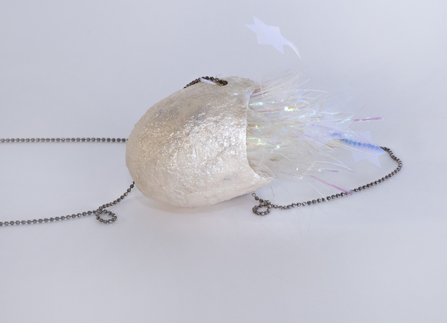 Pendant made of an open pearlwhite silk cocoon with a kind of shiny fluffy fur with stars oozing out of its inside