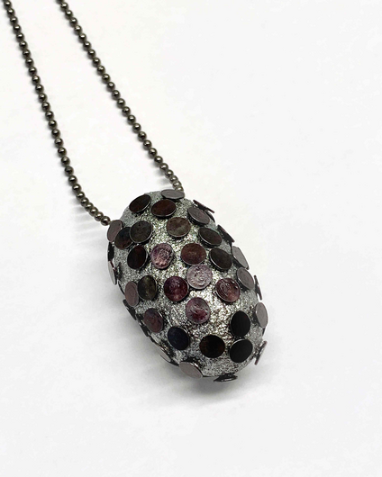 Closed silver silk cocoon, pierced with many flat black nails, on a black silver chain