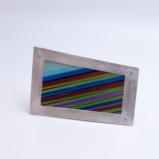 Irregular angular brooch with a silver frame and canvas in colourful fine stripes, it looks like a framed picture