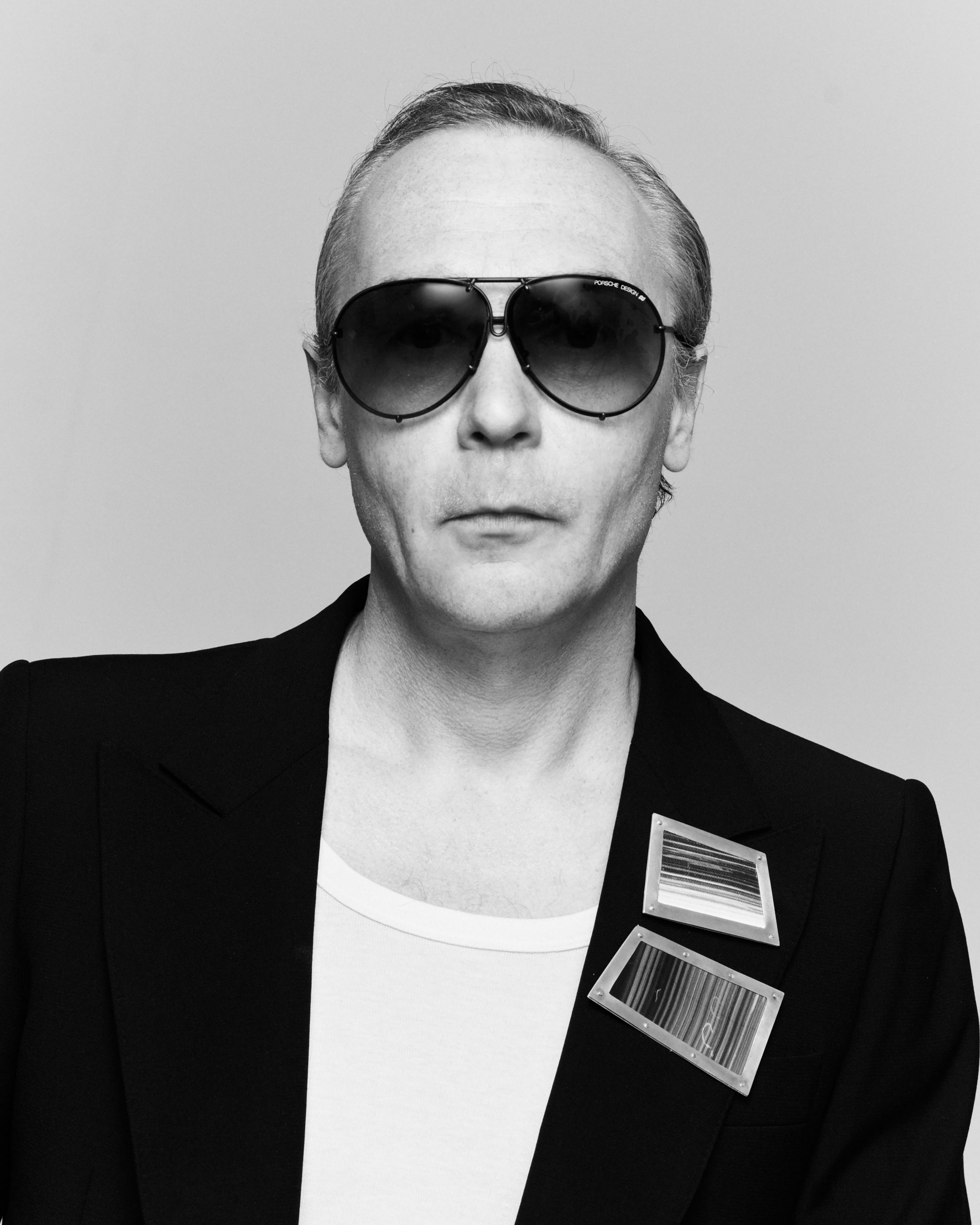 Artist Robert Jelinek wears two brooches on the lapel of the black jacket and sunglasses, his hair is strictly combed back