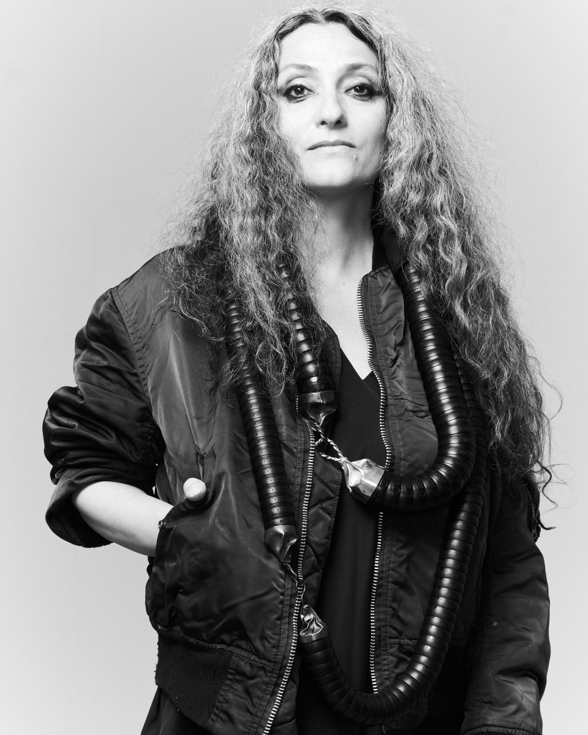 Künstlerin Maja Vukoje trägt zwei schwere Schlauchketten von Ela Nord über einem schwarzen Blouson, ihre langen Haare sind offen, eine Hand ist in ihrer Tasche